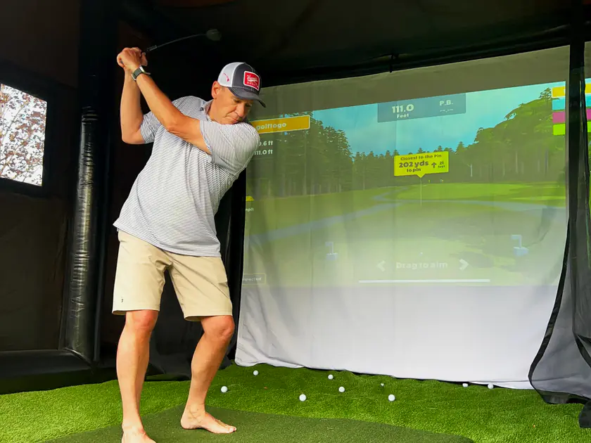Guest at the top of his backswing on a mobile golf simulator at a ward activity