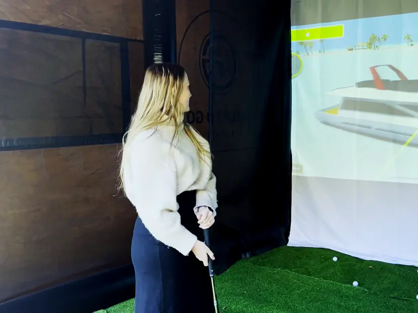 Guest watching her shot land in Boat Blast on a portable golf simulator at a group party