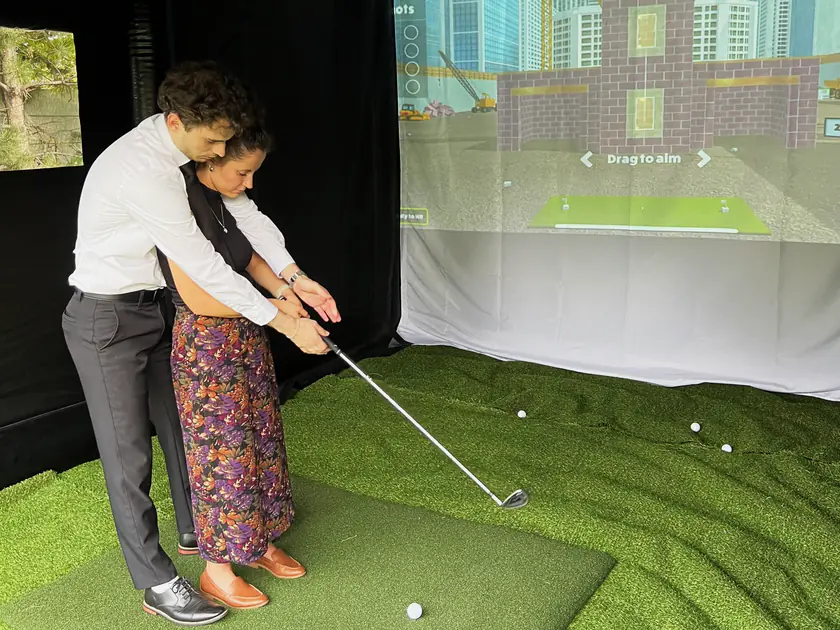 Couple sharing a swing inside a portable golf simulator at a South Jordan, Utah celebration