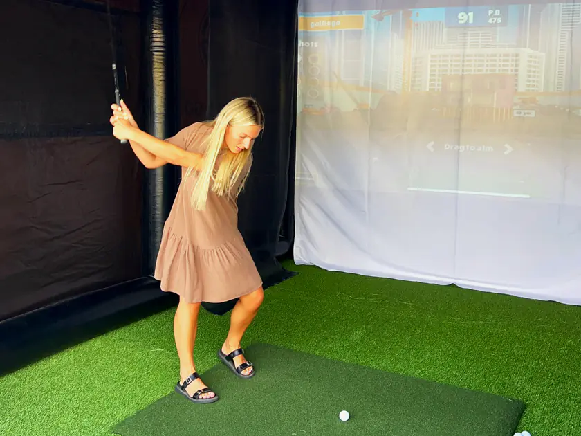 Woman at the top of her backswing in a portable golf simulator at a Spanish Fork, Utah party