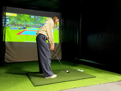 Guest lining up a shot on a golf simulator minigame at a party in Draper, Utah
