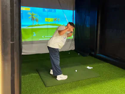 Guest at the top of his backswing on a portable golf simulator at a West Jordan, Utah event