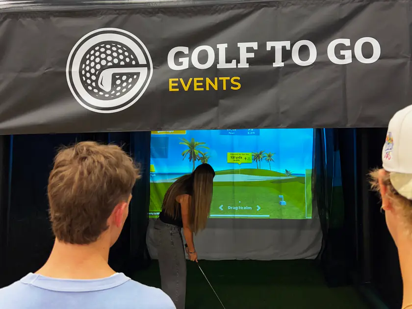 Friends watching a guest take her shot on a mobile golf simulator in Spanish Fork