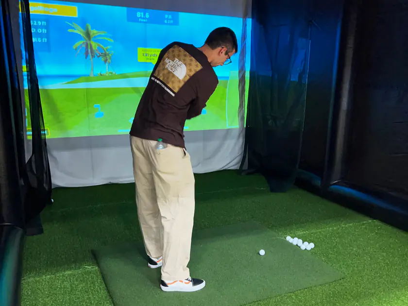 Student lining up a shot on a portable golf simulator at the Provo Rec Center