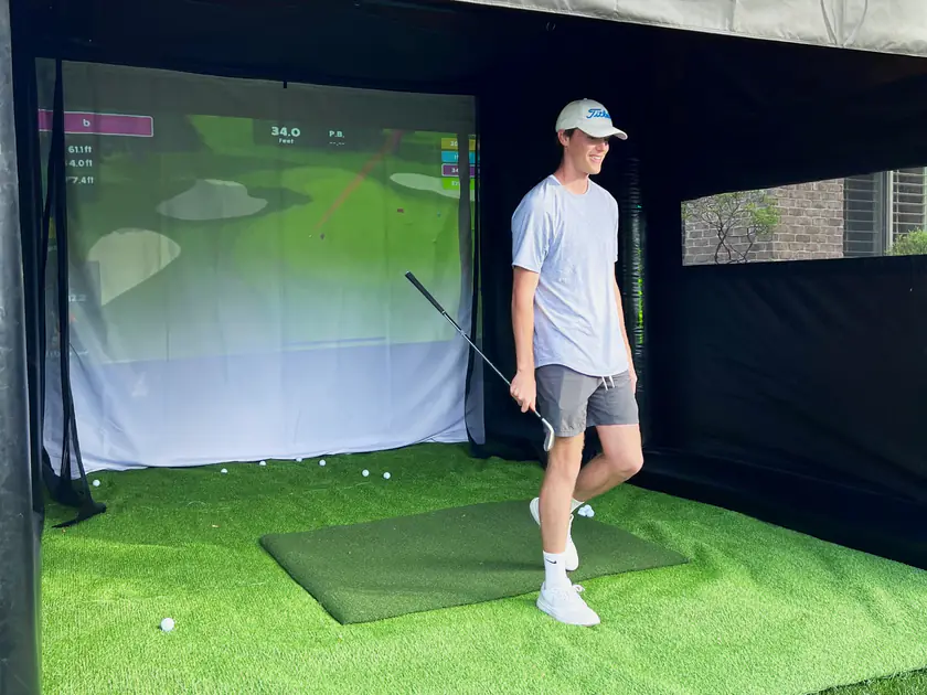 Groomsman smiling as he walks out of the Golf to Go Events golf simulator tent at a bachelor party