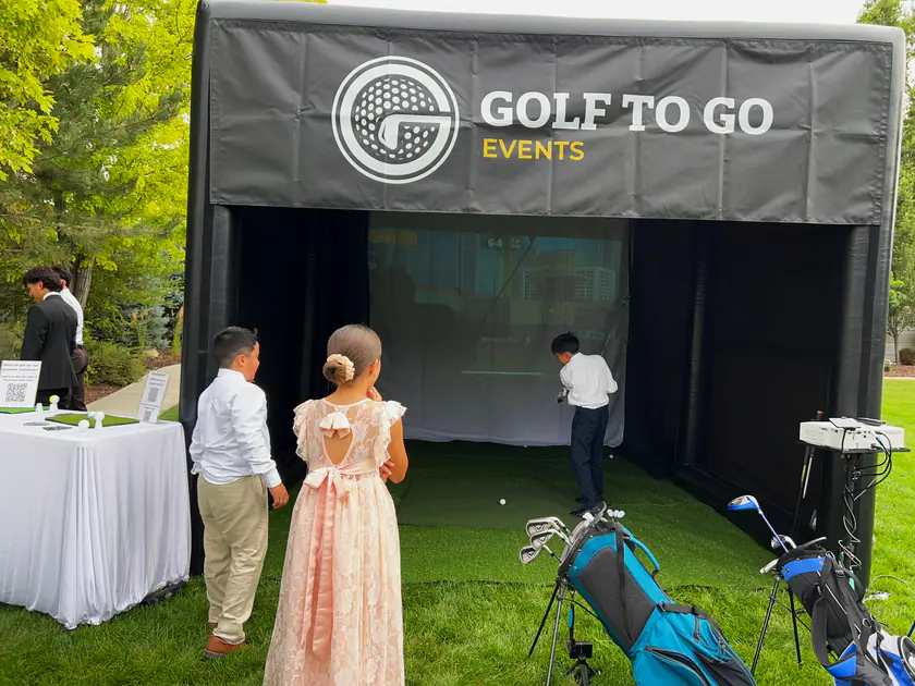 Guests watching a player inside the Golf to Go Events golf simulator tent at an American Fork, Utah event